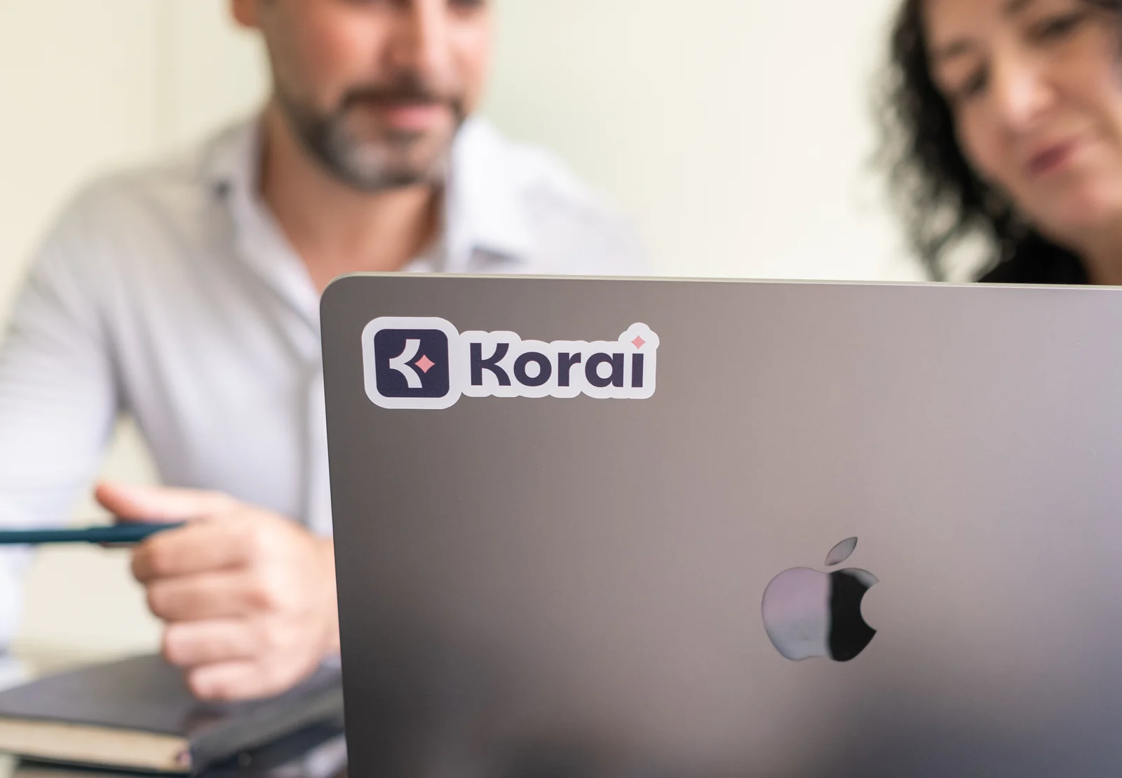 Korai branding on a laptop during a team discussion