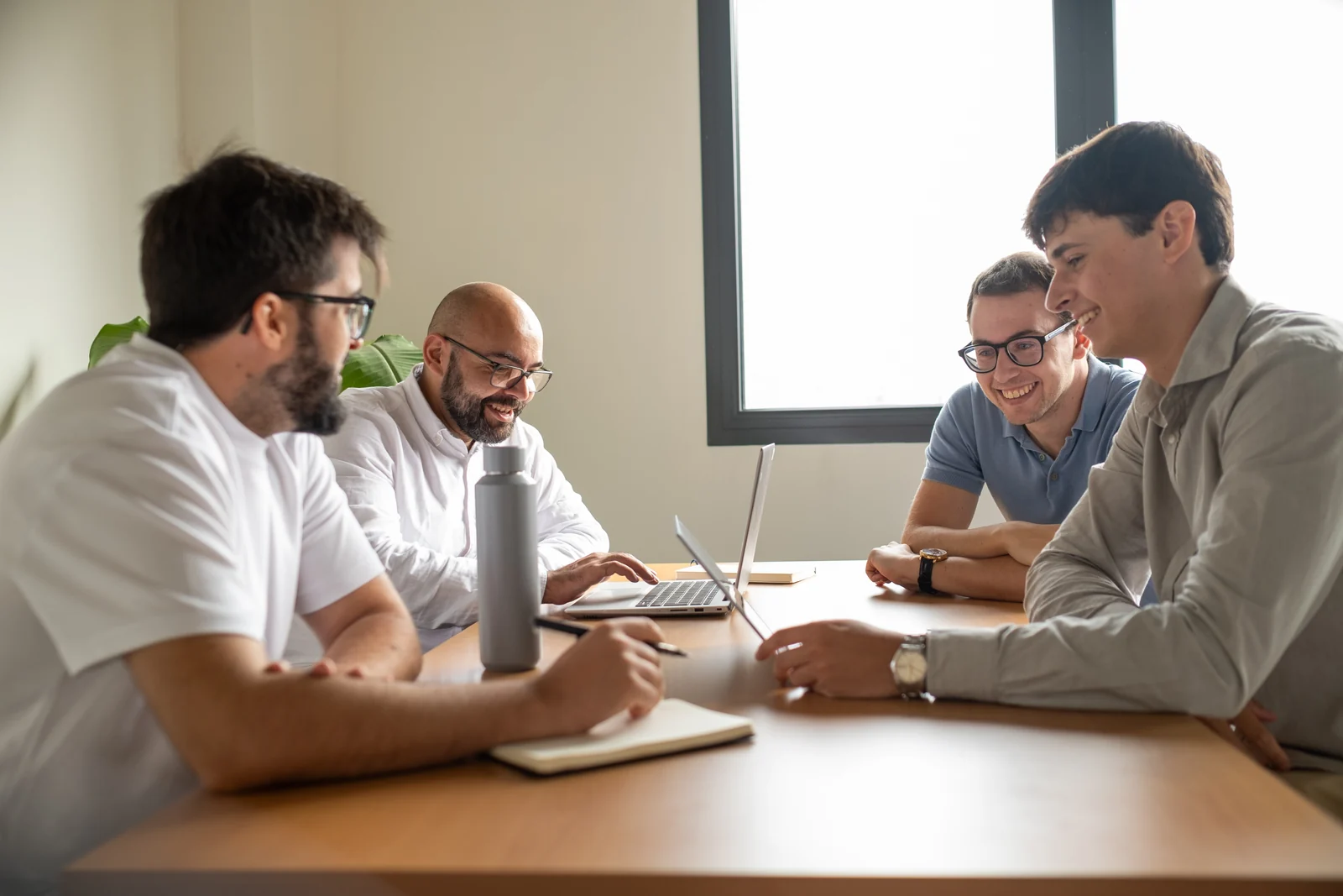 Four Lessthan3 colleagues discussing work around a meeting table
